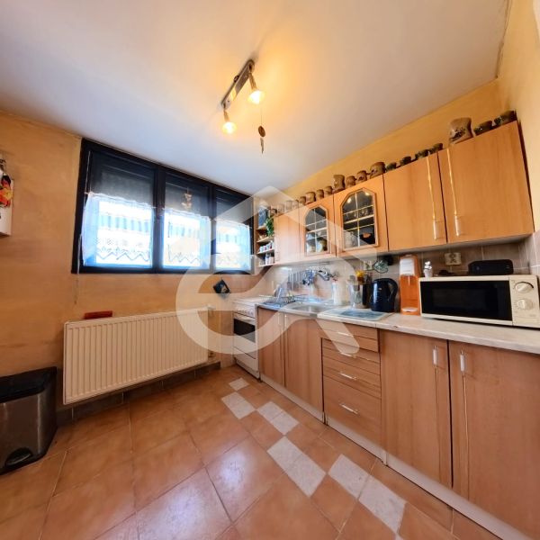 A kitchen with brown cabinets and a spacious window in a family house.