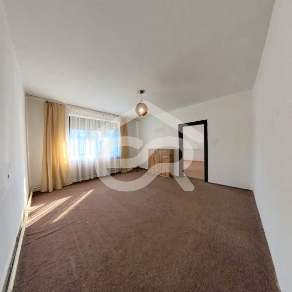 Living room in a family house with carpeted floor, curtains, and light.