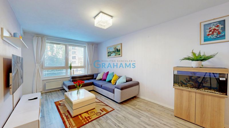 Living room in a 3-room apartment with a sofa, an aquarium, a plant, and a floor with a wooden decor.