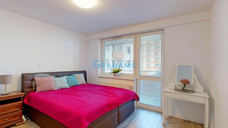 Bedroom with a large bed, nightstand, and mirrored dressing table in a 3-room apartment.