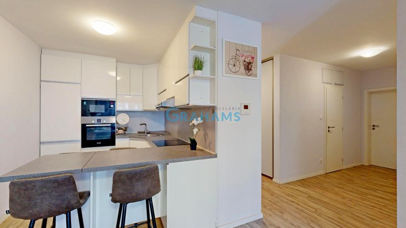 A kitchen with a bar counter and a wooden decor floor in a 3-room apartment.