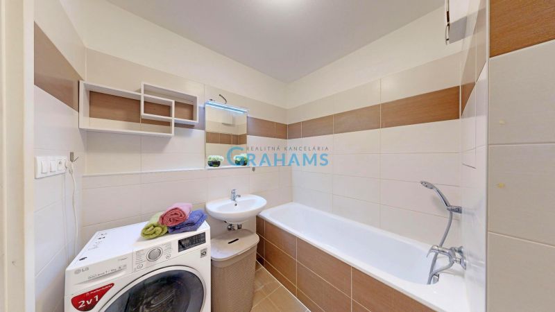 A bathroom in a 3-room apartment with a bathtub, washing machine, and modern tiling.