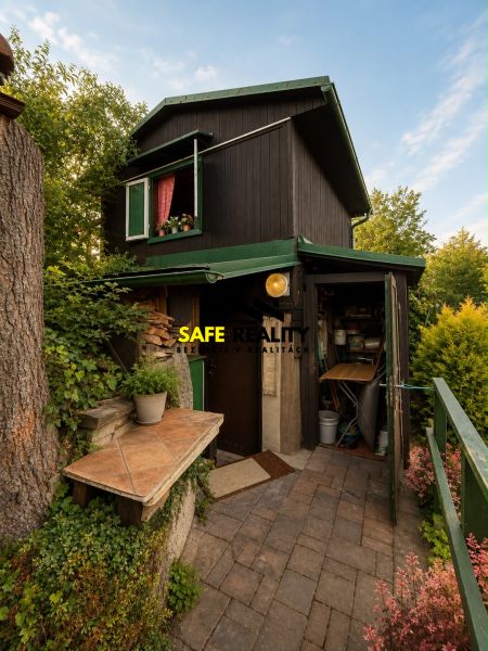 Black cottage in Žilina with greenery and rustic details in the exterior.