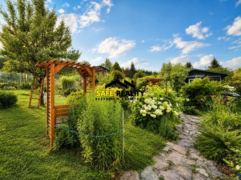 A garden by the cottage in Žilina with a wooden pergola and flower beds.