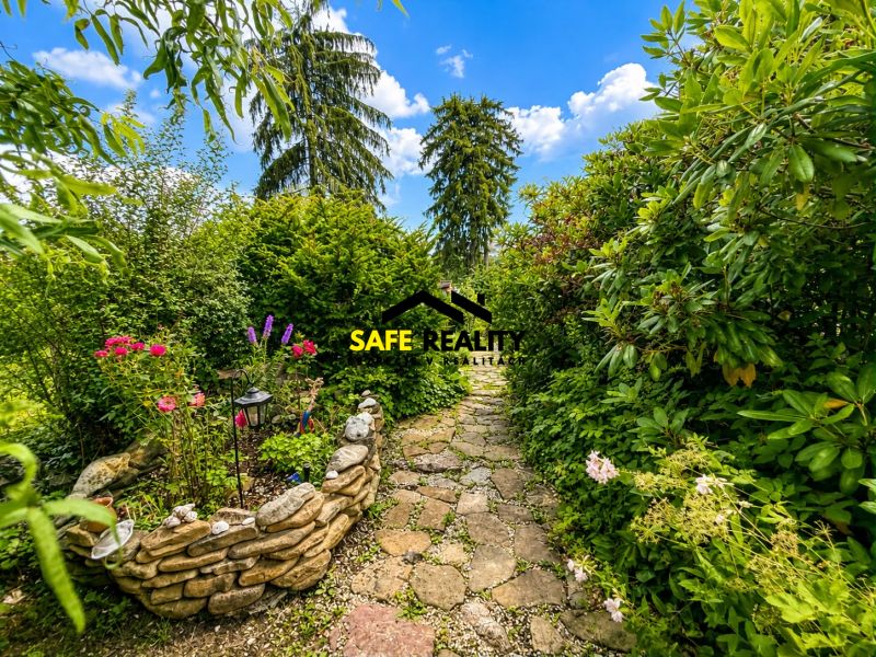 A garden by the cottage in Žilina with a stone path and a flower bed.