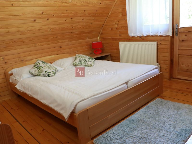 A bedroom in a cabin with wooden paneling, a bed, and a floor with a wooden decor.