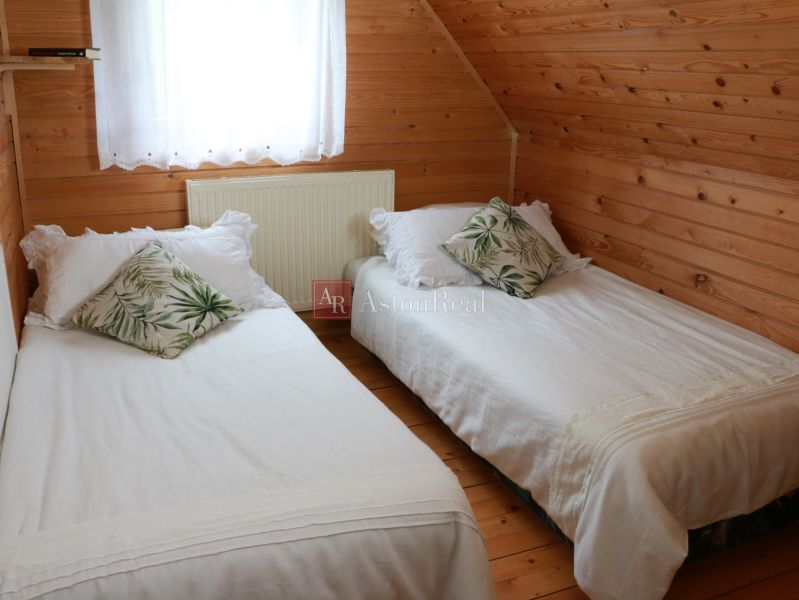 A cabin bedroom with wooden paneling, two beds, and decorative pillows.