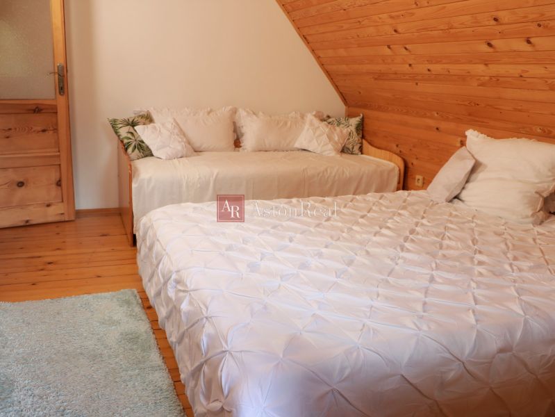 A bedroom in a cottage with two beds, an attic, and a floor with a wooden decor.