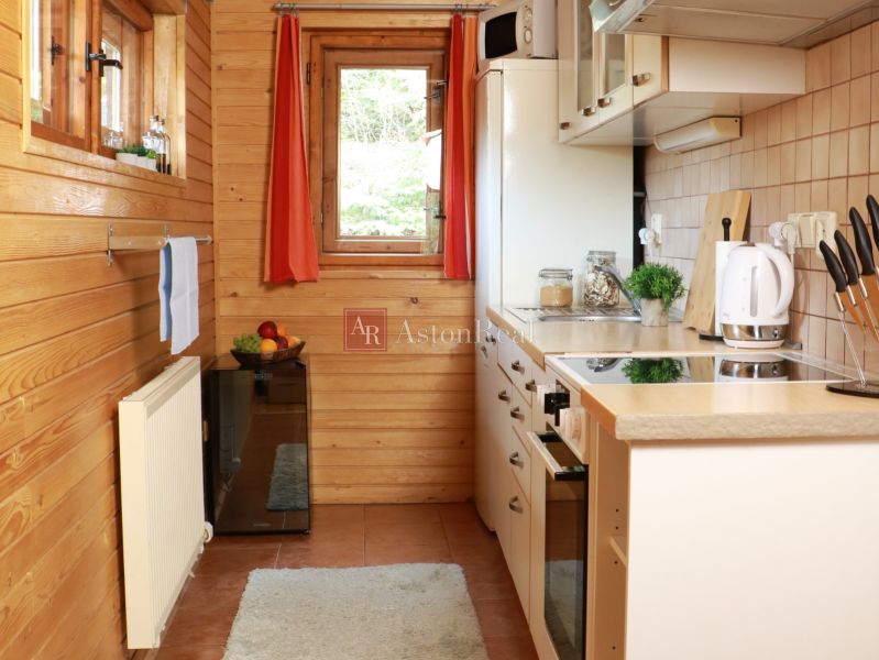 A kitchen in a cabin with wooden decor, white appliances, and a window with a view.