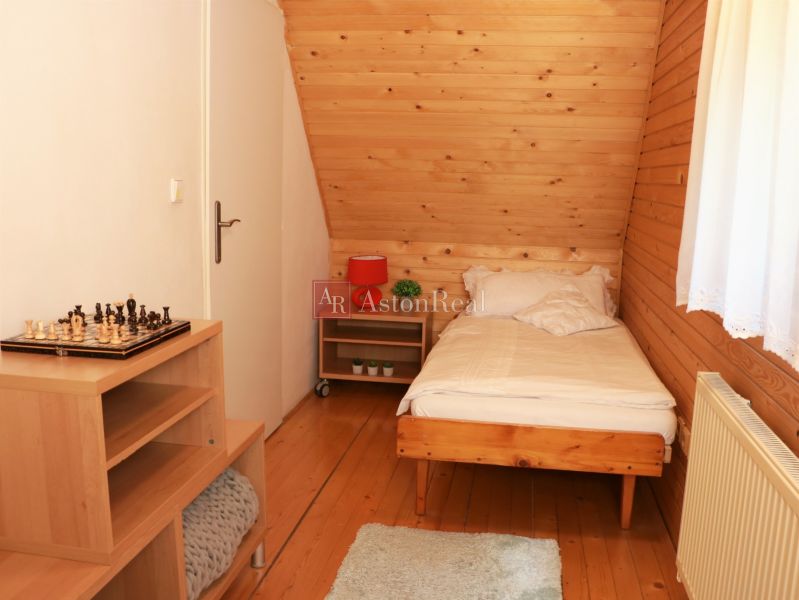 Single room with wood-patterned flooring, a chessboard on the table, and a window with a white curtain.