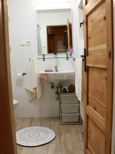 A bathroom in a cottage with a sink, mirror, and floor with a wooden decor.