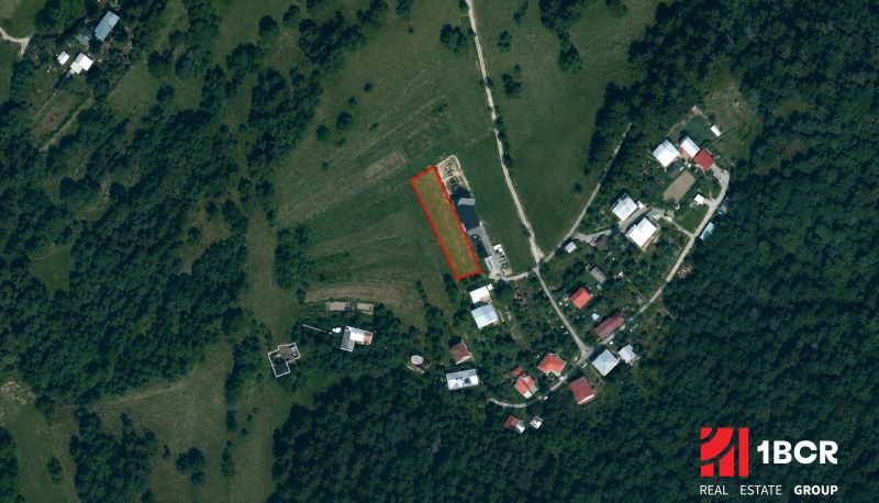Aerial view of agricultural and forest lands near the village of Oščadnica with visible buildings.