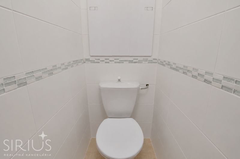 White toilets with patterned tiles and narrow space in commercial premises.