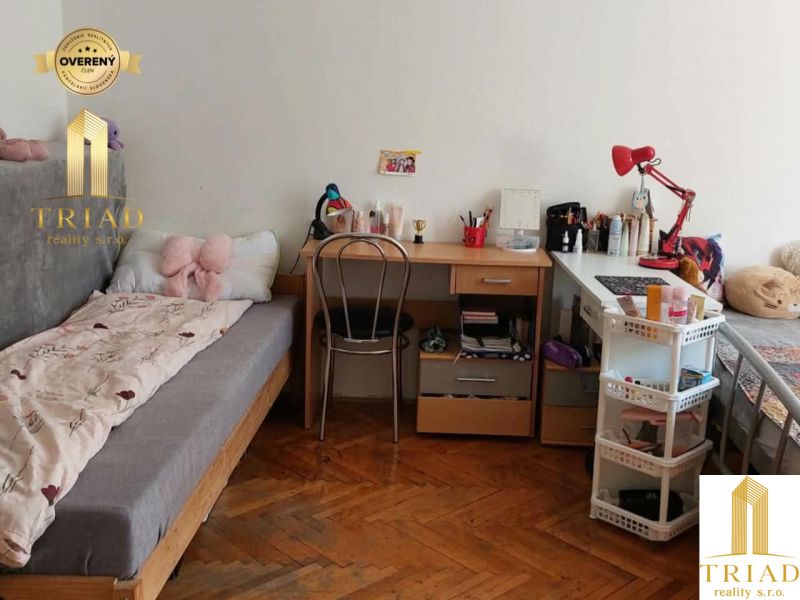 Student room in a one-room apartment with a wooden decor floor and simple furniture.