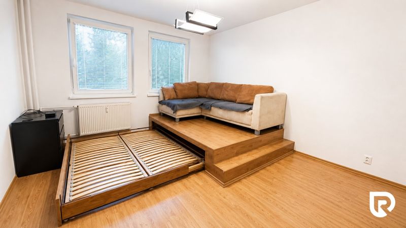 Living room with a corner sofa and a pull-out bed in a 2-room apartment, floor with wood decor.