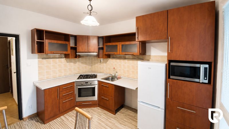 A kitchen in a 2-room apartment with wooden cabinets and appliances.