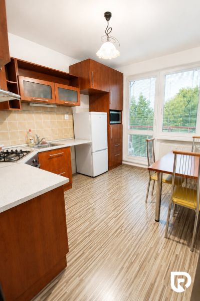 A kitchen in a 2-room apartment with a wooden decor floor and large windows.