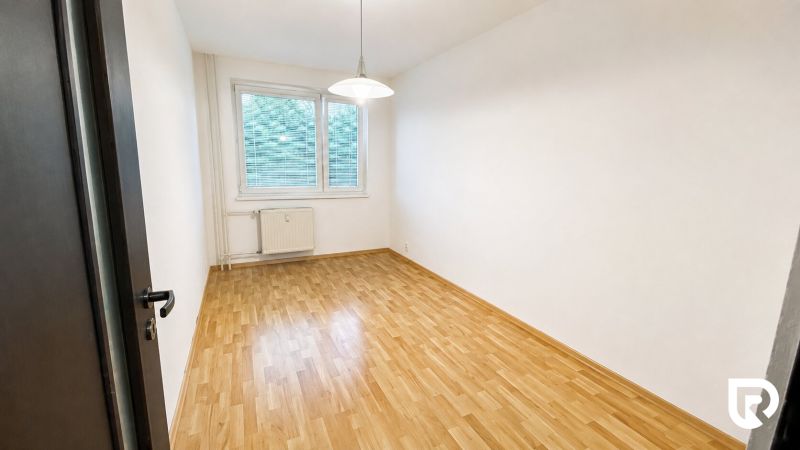An empty room in a 2-room apartment with a wood-patterned floor and white walls.