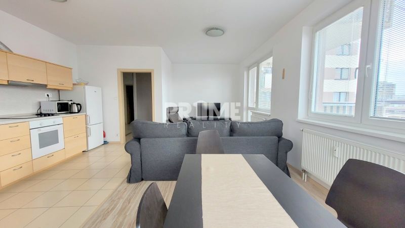 Two-room apartment with a kitchen, living room, sofa, and dining table; floor with wood decor.