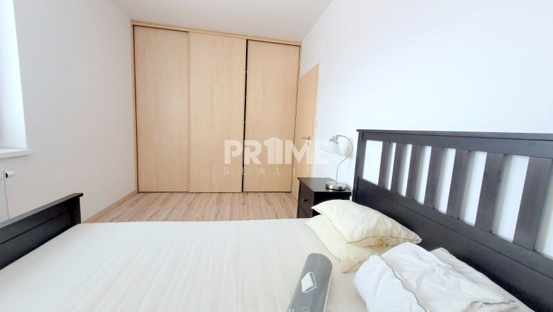 Bedroom in a 2-room apartment with a double bed, built-in wardrobe, and a lamp.