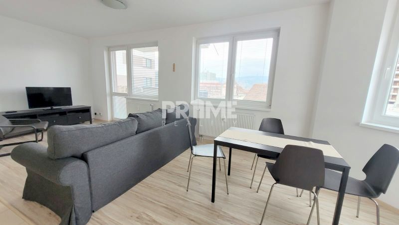 Living room with a sofa, television, and dining table in a 2-room apartment.