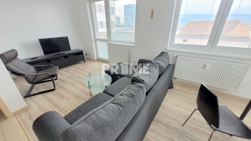 Living room of a 2-room apartment with a sofa, armchair, and TV, floor with wooden decor.