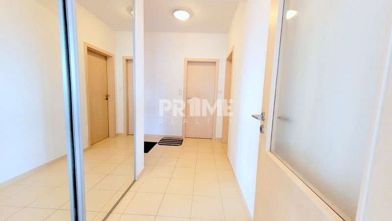 Hallway in a 2-room apartment with a large mirror, tiled floor, and white walls.