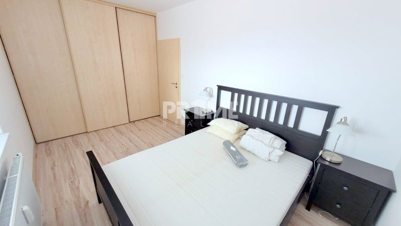 A bedroom with dark furniture and a wood-patterned floor in a 2-room apartment.