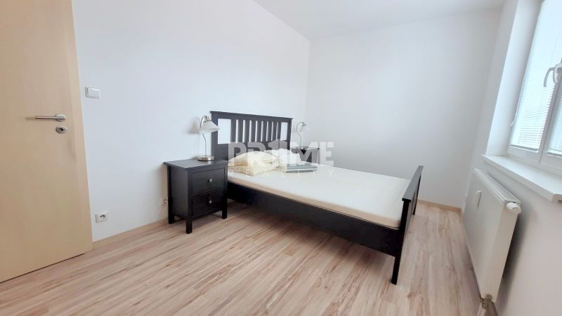 Bedroom in a 2-room apartment with a bed, nightstand, and wooden decor flooring.