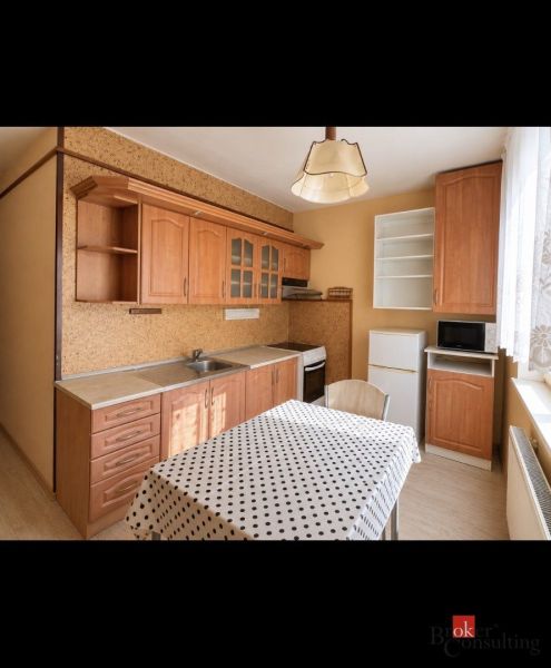 The kitchen in the 2-room apartment has a wooden-patterned floor and a polka dot tablecloth.