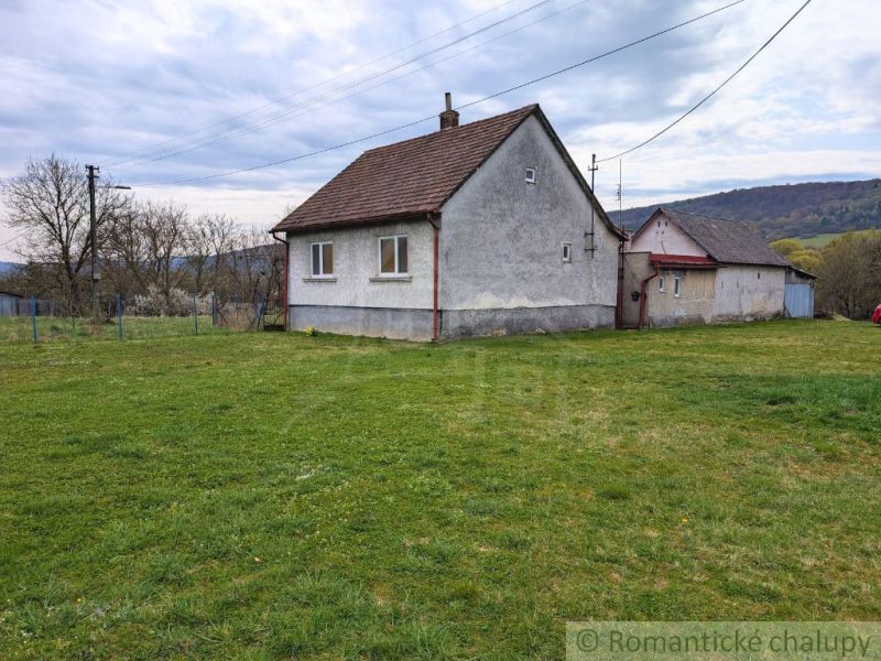 A family house in the village of Volica with an adjacent green garden and a hilly backdrop.
