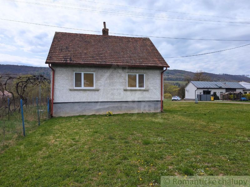 A family house in Volica with a grassy plot and hilly landscape in the background.