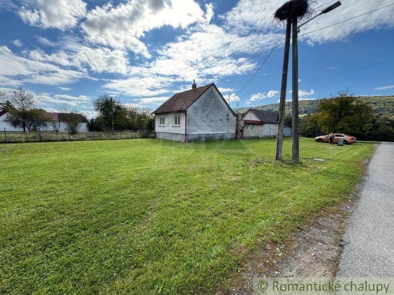 A family house in the village of Volica with a green lawn, an electric pole, and a parked car.