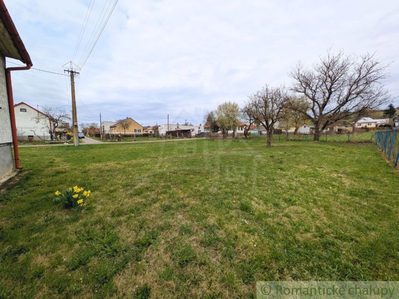 A family house in Volica with an extensive lawn and trees, with more houses in the background.