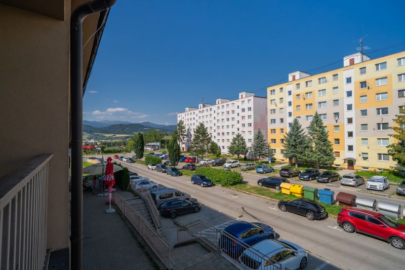 Street of the May Uprising of the Czech People in Brezno with apartment buildings and parked cars.