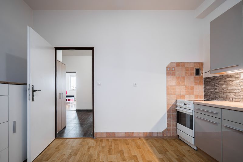 A kitchen in a 2-room apartment with tiles, a wooden decor floor, and an oven.