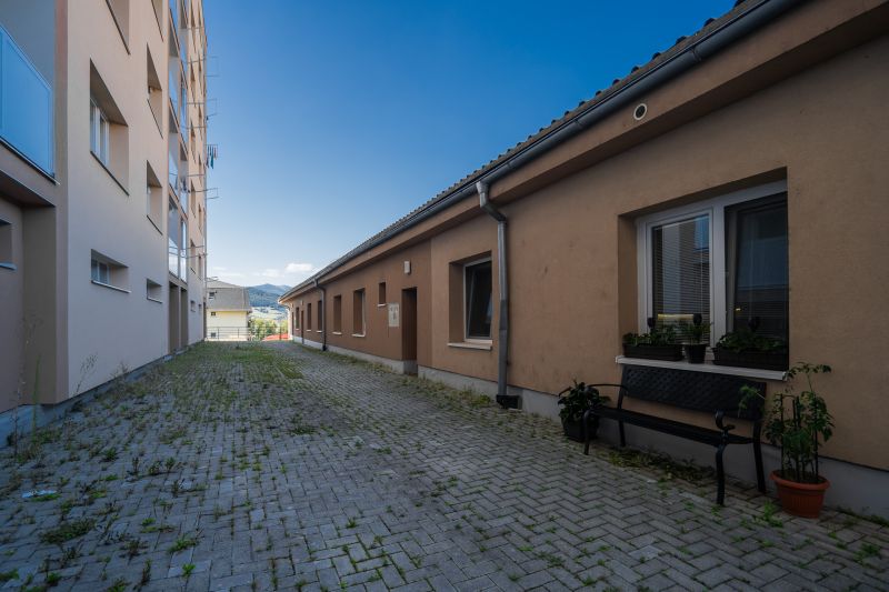 The area with interlocking paving stones between the buildings on the street Májového povstania českého ľudu in Brezno.