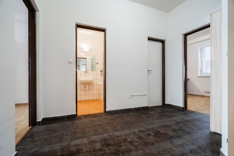 An entrance hall with dark tiles in a 2-room apartment, bathroom in the background.