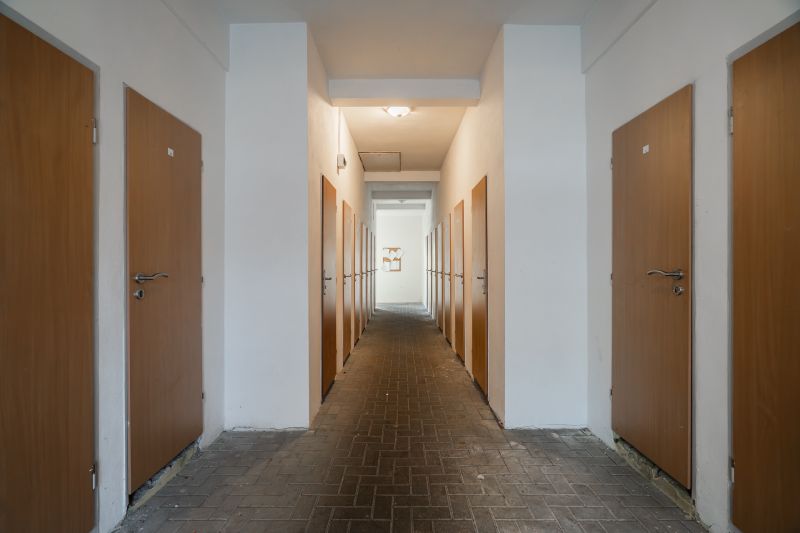 A corridor with symmetrically arranged doors, tiled floor, simple lighting.