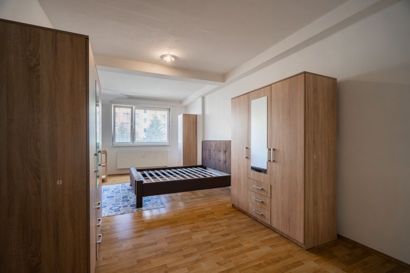 Bedroom in a 2-room apartment with a bed, wardrobes, and a floor with a wooden decor.