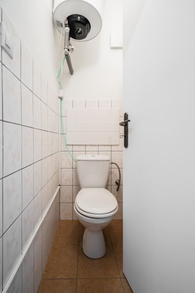 Bathroom in a 2-room apartment with a toilet and a boiler on the wall.