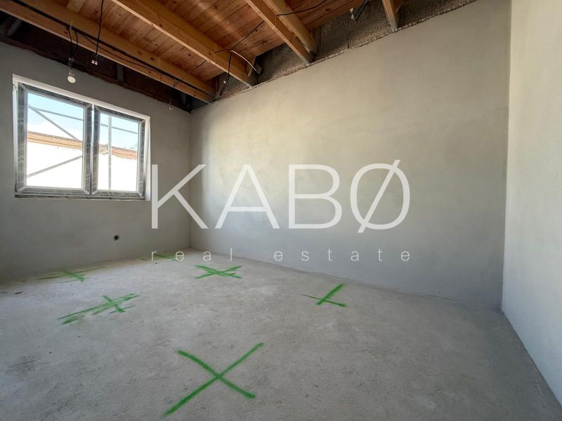 An empty room with a wooden ceiling, plastered walls, a window in a family house.