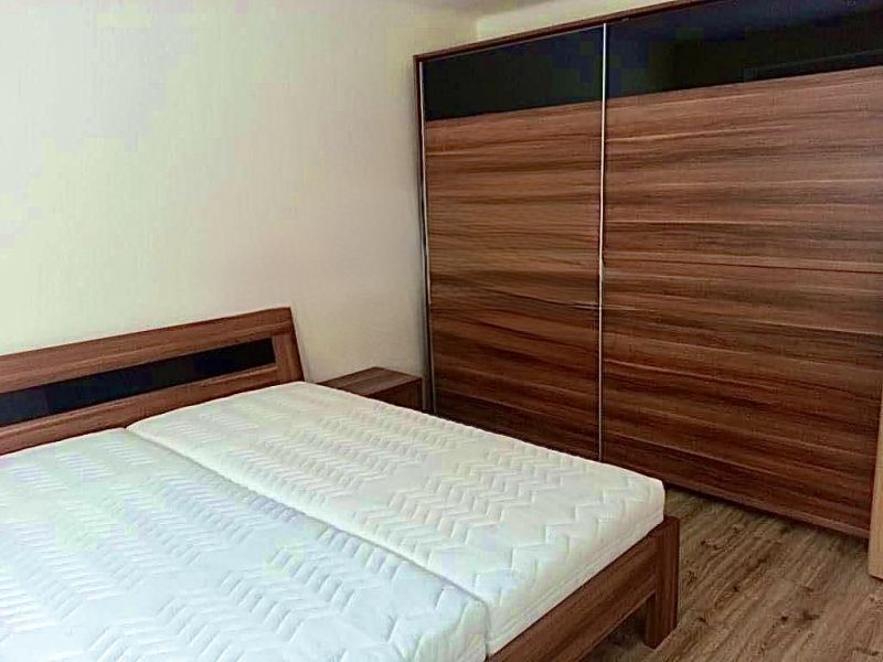 Bedroom in a 2-room apartment with a bed and a large wardrobe, floor with wooden decor.