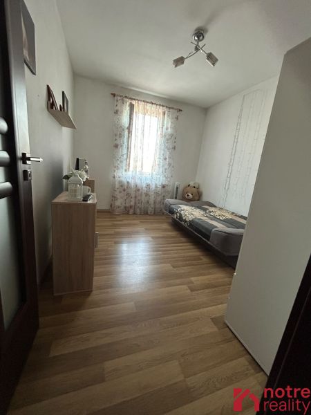 A room in a 2-room apartment with a wooden decor floor and simple furnishings.