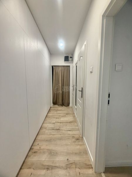 A hallway with white walls and a wooden decor floor in a 3-room apartment.