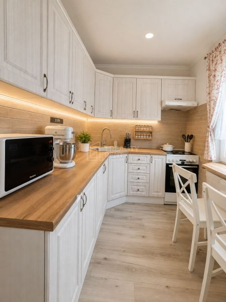 A kitchen in a three-room apartment with a wooden decor floor and white furniture.