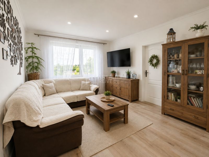 Living room in a 3-room apartment with a comfortable sofa and a wooden-patterned floor.