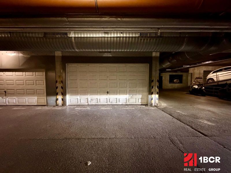 The interior of garages with closed doors and parked vehicles.