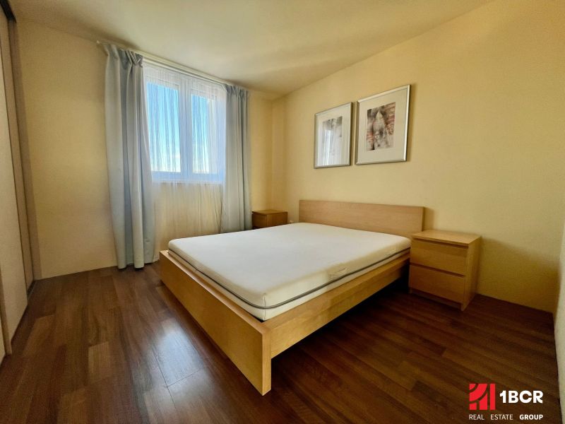 A bedroom in a two-room apartment with a bed and a wooden decor floor.