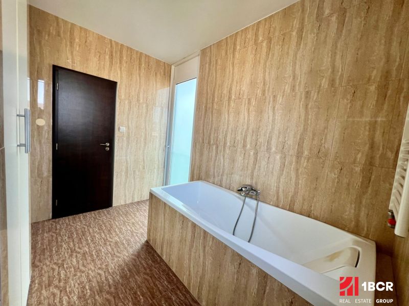 A bathroom with a bathtub and tiles in a 2-room apartment.